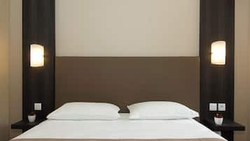 Una habitación de hotel con una cama grande, dos mesitas de noche y luces fijadas en la pared.