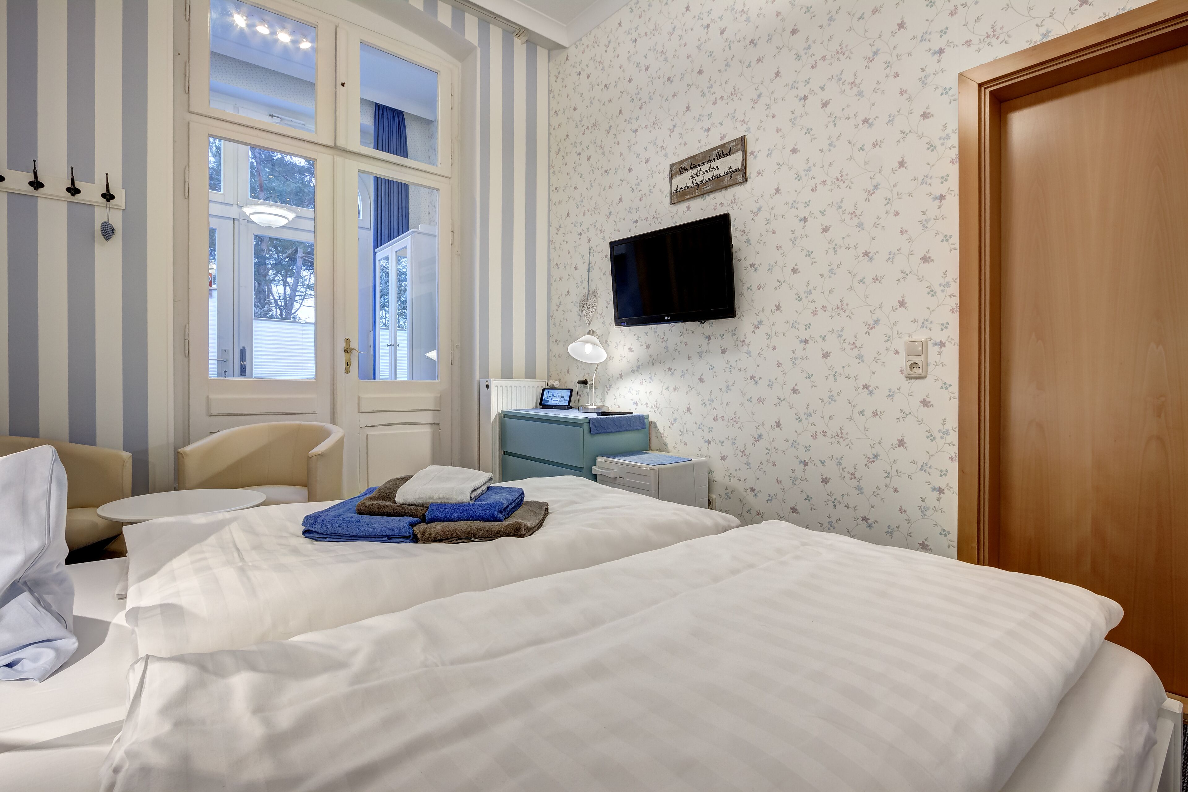 Habitación de hotel con dos camas, un escritorio, una silla, un televisor y una ventana con persianas.