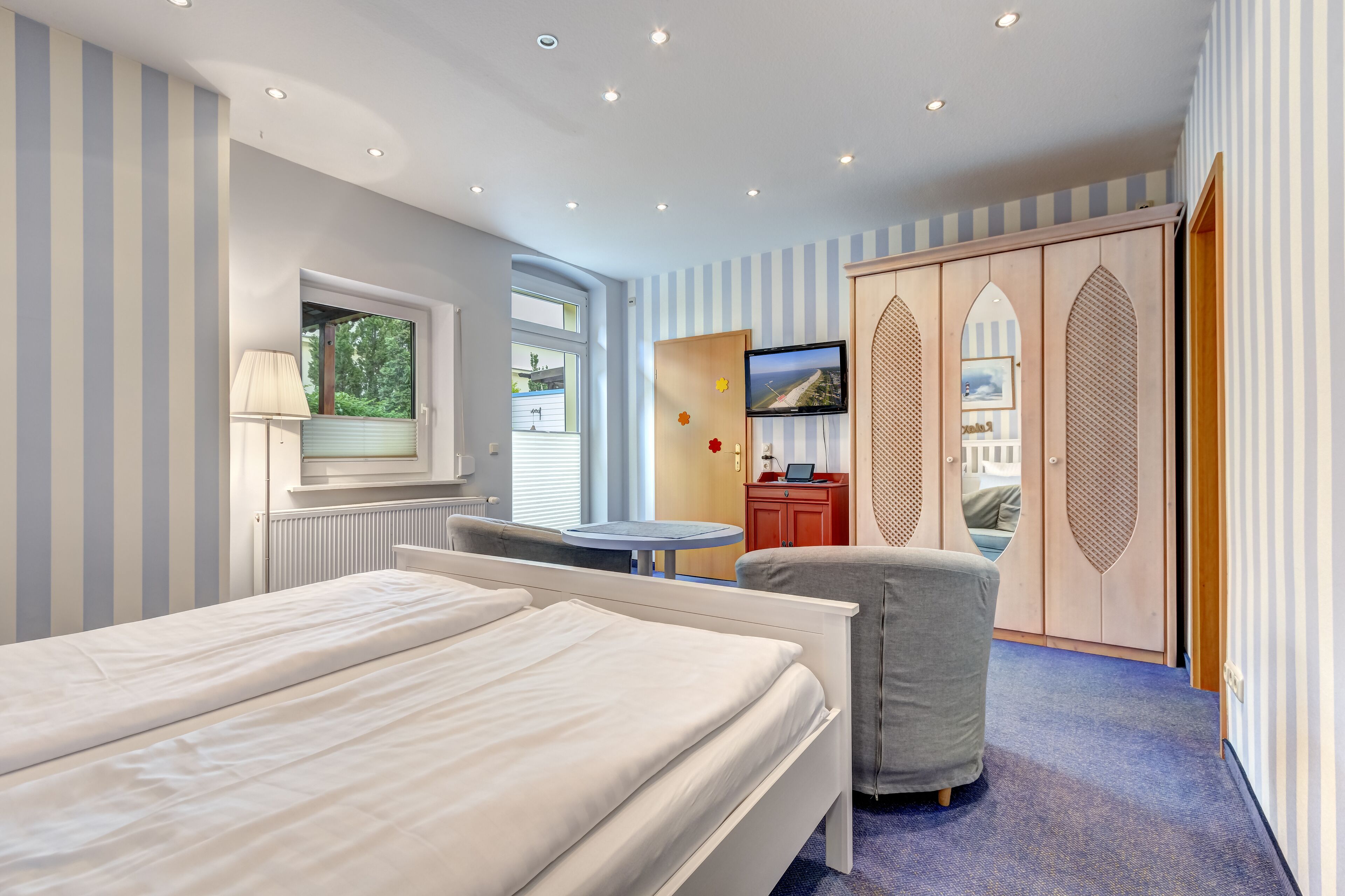 Een slaapkamer met twee bedden, een bureau, een stoel, een televisie en een kledingkast.