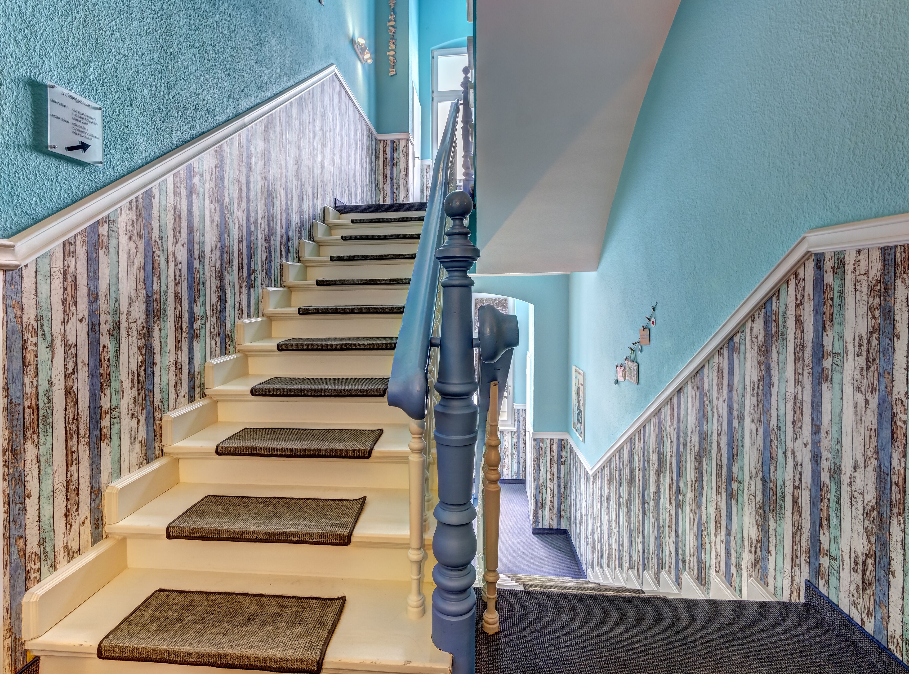 Un escalier avec une rampe bleue, des marches blanches et un mur à texture.