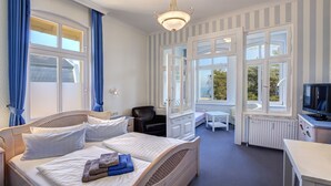 Hotellihuone, jossa on sänky, työpöytä, tuoli ja televisio.