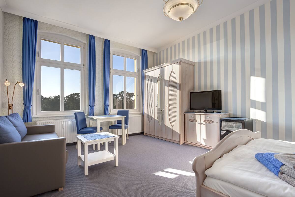 Una habitación de hotel con una cama, un escritorio con silla, un armario y un televisor.