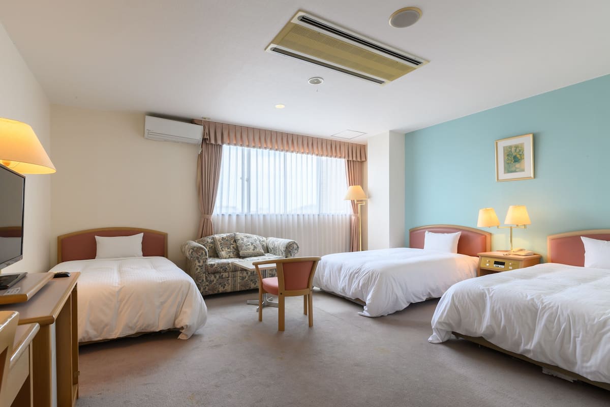 Ett hotellrum med två sängar, ett skrivbord, en stol och en tv.