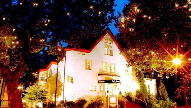 A white building with a red roof, a sign reading "Park-Restaurant," and a staircase leading to the entrance. - Parkhotel Herne (Herne)