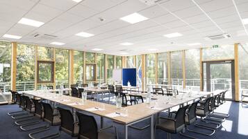 A conference room with long tables, chairs, and a whiteboard.