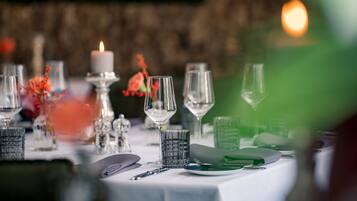 Une table mise pour un repas, avec de la belle verrerie, une bougie et un vase rempli de fleurs.