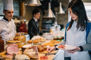 A buffet with various food items and a person serving themselves. - Antica Corte Pallavicina (Polesine Zibello)