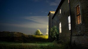 An abandoned brick building with large windows and a grassy area in front. - Antica Corte Pallavicina (Polesine Zibello)