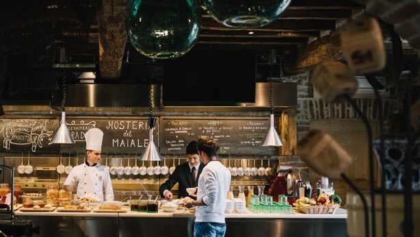 A restaurant kitchen with chefs preparing food, a chalkboard menu, and hanging pots. - Antica Corte Pallavicina (Polesine Zibello)