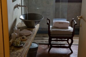 A bathroom with a large metal basin, a wooden chair with a towel, and a small table with toiletries. - Antica Corte Pallavicina (Polesine Zibello)