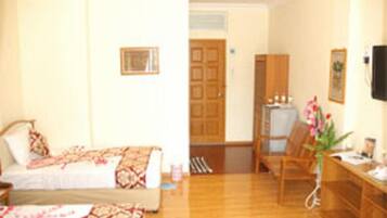 A hotel room with a bed, a desk, a chair, and a television.
