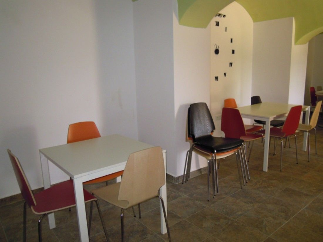 Un comedor con una mesa y sillas blancas, un reloj en la pared y piso de baldosas.