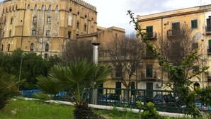 Un edificio histórico con una torre circular, rodeado de vegetación y automóviles estacionados.