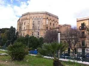 A historic building with a round tower, surrounded by greenery and modern buildings. - L ' Arabo e il Normanno (Palermo)