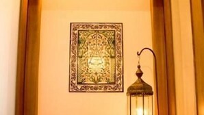 Un pasillo con una lámpara decorativa, una obra de arte en la pared y una pequeña mesa con lámpara.