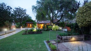 A residential property with a well-maintained lawn, garden beds, and a paved walkway leading to a house with a tiled roof. - Gardenview Guest House (Gqeberha (Port Elizabeth))