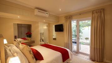 Ein Hotelzimmer mit Bett, Fernseher, Badezimmer und einer Glasschiebetür nach draußen.