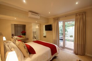 A hotel room with a bed, a TV, a bathroom, and a sliding glass door to the outside. - Gardenview Guest House (Gqeberha (Port Elizabeth))