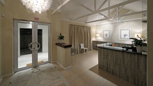 A hotel lobby with a reception desk, a glass door entrance, a chandelier, and a view of the outside. - Gardenview Guest House (Gqeberha (Port Elizabeth))