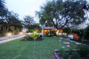 A residential property with a well-maintained lawn, a small tree, and a house with a tiled roof. - Gardenview Guest House (Gqeberha (Port Elizabeth))