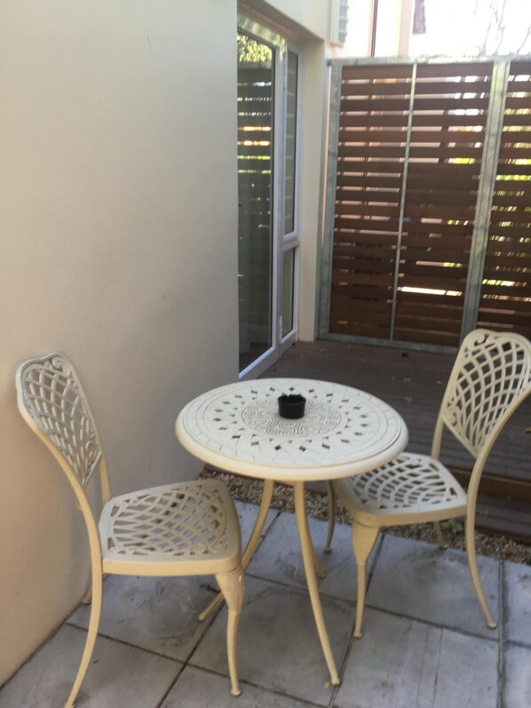 Un pequeño patio al aire libre con una mesa redonda y dos sillas.