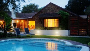 A swimming pool with lounge chairs, a brick house with a chimney, and a well-maintained garden. - Gardenview Guest House (Gqeberha (Port Elizabeth))