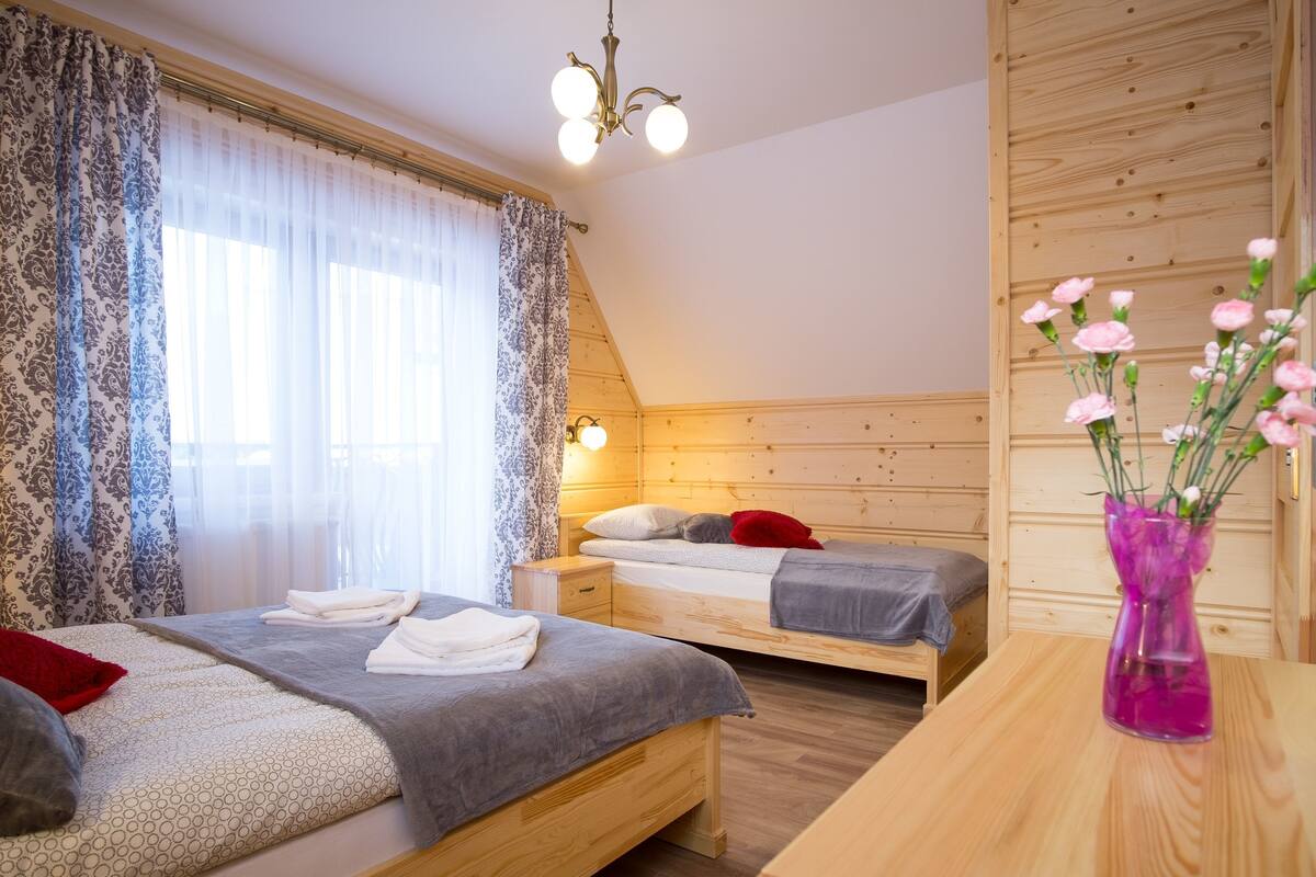 Ein Schlafzimmer mit zwei Betten, einem Holzkopfstück, einem Nachttisch und einer Vase mit Blumen.