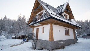 Ein Chalet mit steiler Satteldachform, Holzbalkonen und einem Balkon.