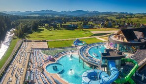 A water park with a large pool, slides, and a scenic mountain backdrop. - Domki przy Potoku (Poronin)