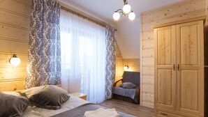 Ein Schlafzimmer mit Bett, Sessel, Kleiderschrank und einem fenster mit Vorhängen.