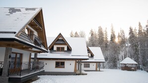 Eine schneebedeckte Lodge mit einem auffälligen Balkon und einer Holzterrasse.