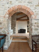 A stone-walled room with a brick archway leading to a wooden staircase.
