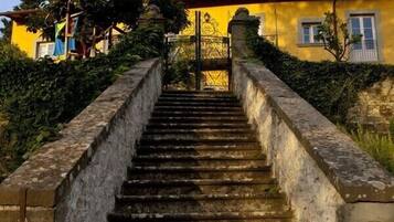 Un escalier en pierre mène à un bâtiment à la façade jaune et au toit rouge.