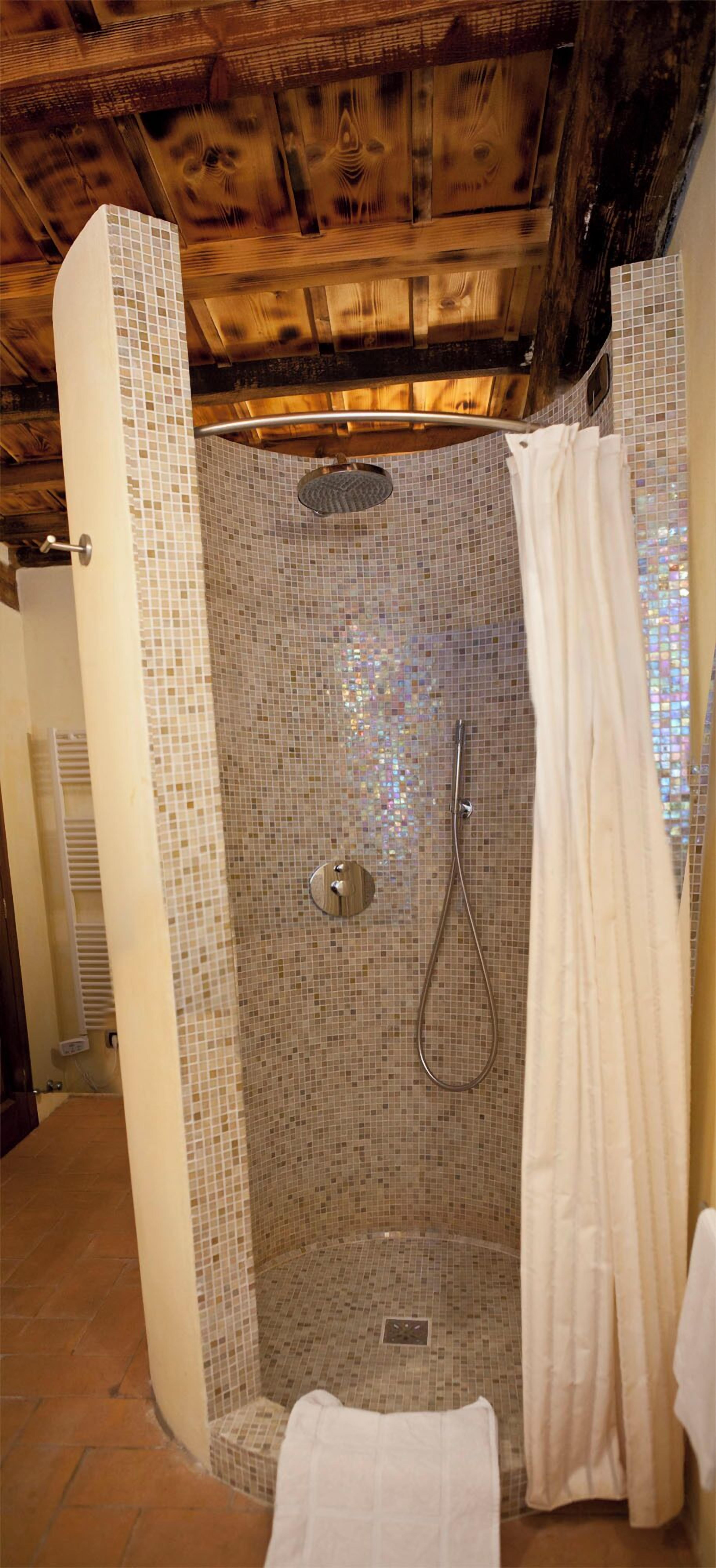 Ein Duschbereich mit Mosaikfliesen, einer Duschbrause und einem Duschvorhang.