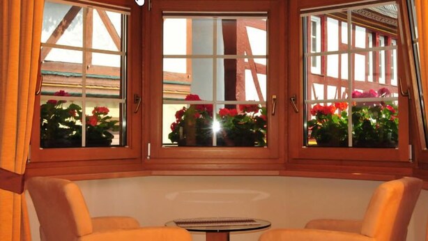 A room with a wooden-framed window, a small round table, and two cushioned chairs. - Weingut Gästehaus Derkum (Uerzig)