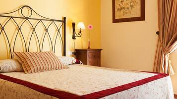 A neatly made bed with a floral bedspread and a red accent at the foot.