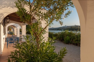An outdoor patio with a pergola, seating area, and a view of a hillside.