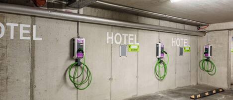 Un garaje de hotel para estacionamiento con múltiples estaciones de carga para vehículos eléctricos, paredes de concreto y un diseño industrial y limpio.