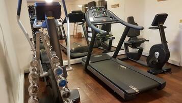 A home gym with a treadmill, elliptical, and weight bench.
