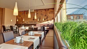Een restaurant met gedekte tafels, hangende吊灯和帶有咖啡豆圖案的壁畫.