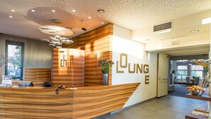 Een receptiebalie met een houten afwerking en een bord met de tekst 'LUNGHE'.