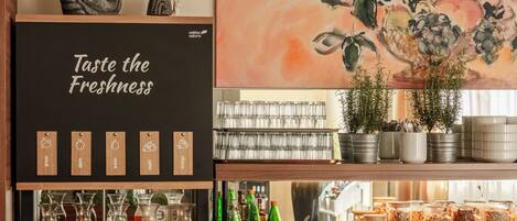 A beverage station with various drink options and a sign that reads 'Taste the Freshness.'
