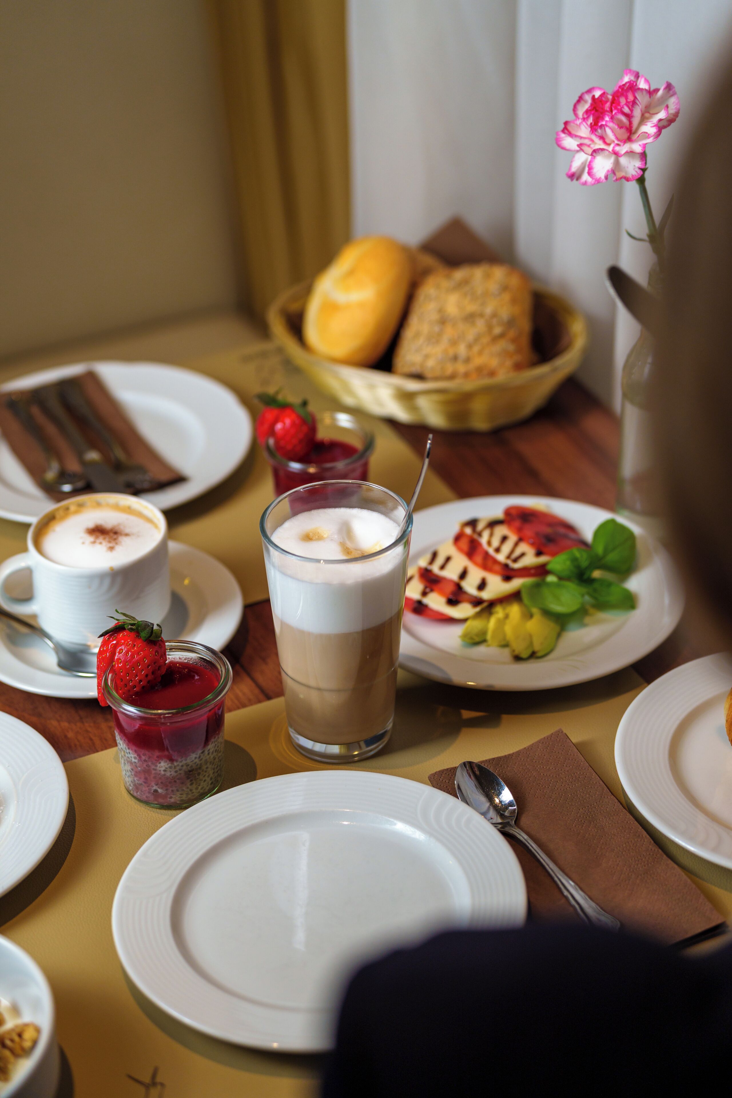 A table set with plates, cups, and a bowl of bread.