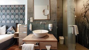 A modern bathroom with a large mirror, a vessel sink, a towel rack, and a glass shower enclosure.