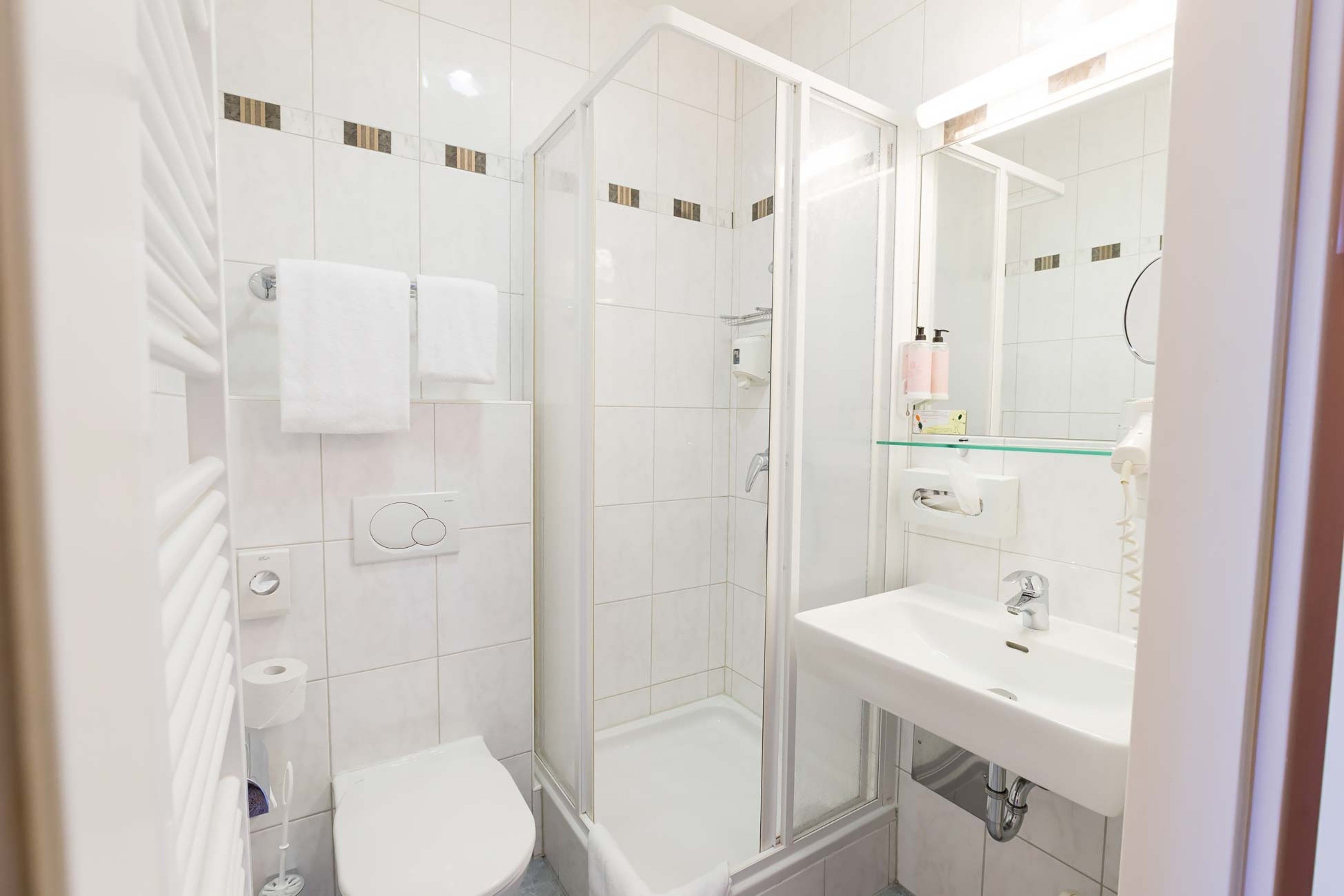Uma casa de banho moderna com cabine de duche em vidro, lavatório branco e sanita.