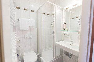 A modern bathroom with a glass-enclosed shower, a white sink, and a toilet.