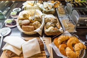 A buffet with various breads, pastries, and cheeses. - Hotel Süd art (Graz)
