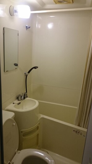 Une petite salle de bain avec des toilettes, un lavabo et une baignoire.