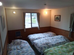 Une chambre d’hôtel avec deux lits, un petit bureau, une fenêtre avec des rideaux et un tableau encadré au mur.