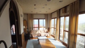 A spacious room with a large window, a sofa, a wooden table, and a lamp. - Rental Lodge WHITE RABBIT Madarao kogen Cottage RABBIT (Iiyama)